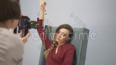模特穿着红色连衣裙，扶手椅上有一条金链。 图片会议